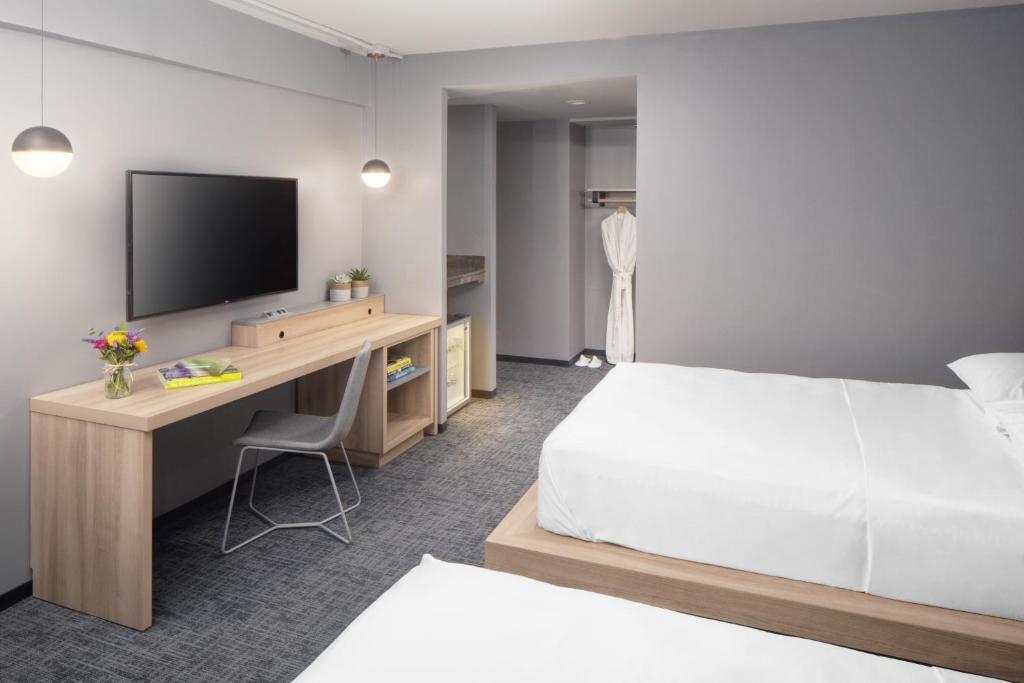 a hotel room with a bed and a desk with a television at Henn na Hotel New York in New York