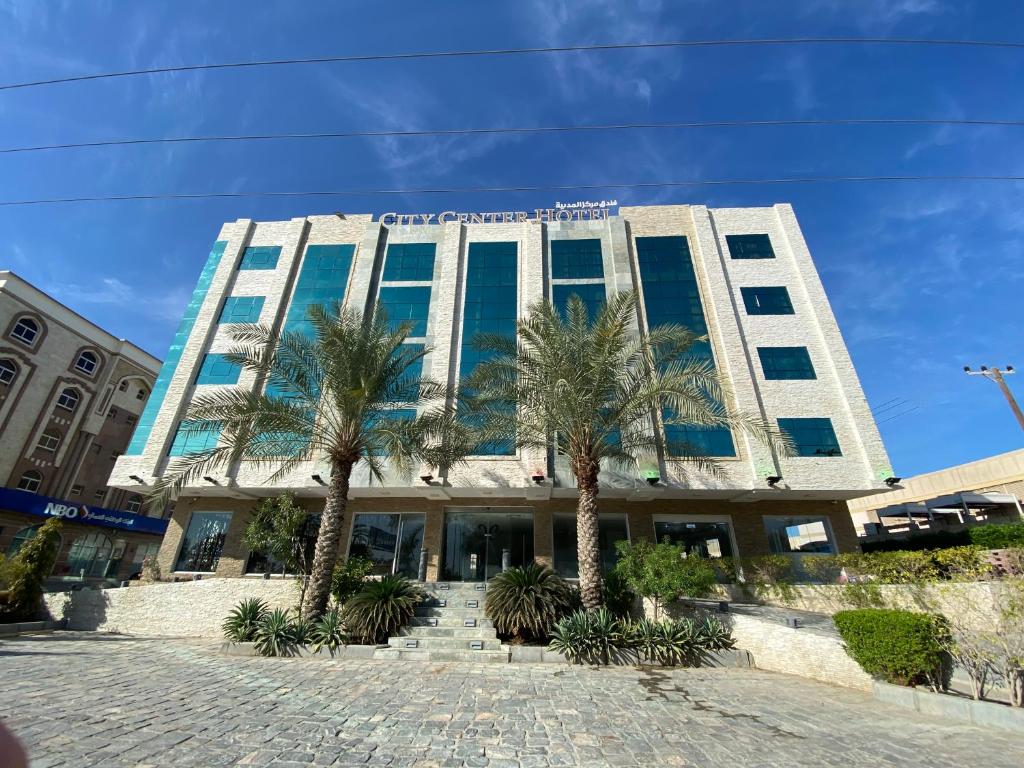 a building with palm trees in front of it at City Center Hotel in Mawāliḩ