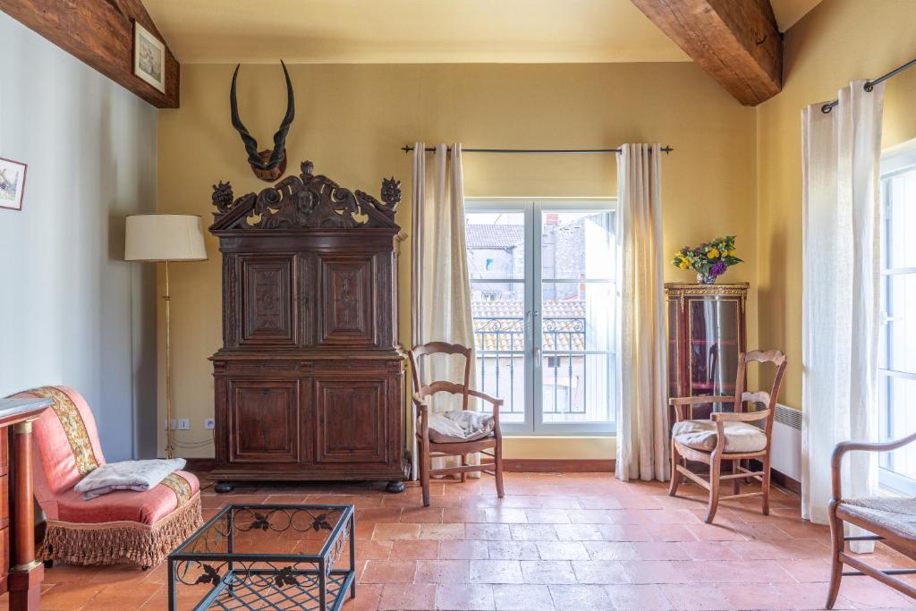 una sala de estar con un gran armario de madera y sillas en Pléiade, en Béziers