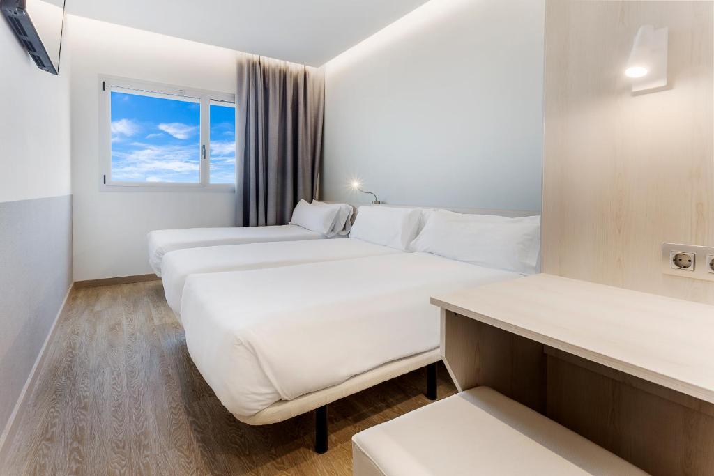 a hotel room with two beds and a window at B&B HOTEL Barcelona Viladecans in Viladecáns