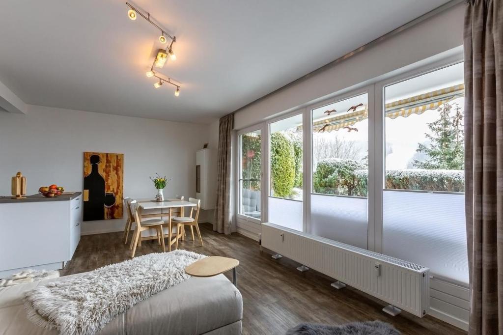 a bedroom with a bed and a table and windows at Ferienwohnung Aartalblick Willingen in Willingen