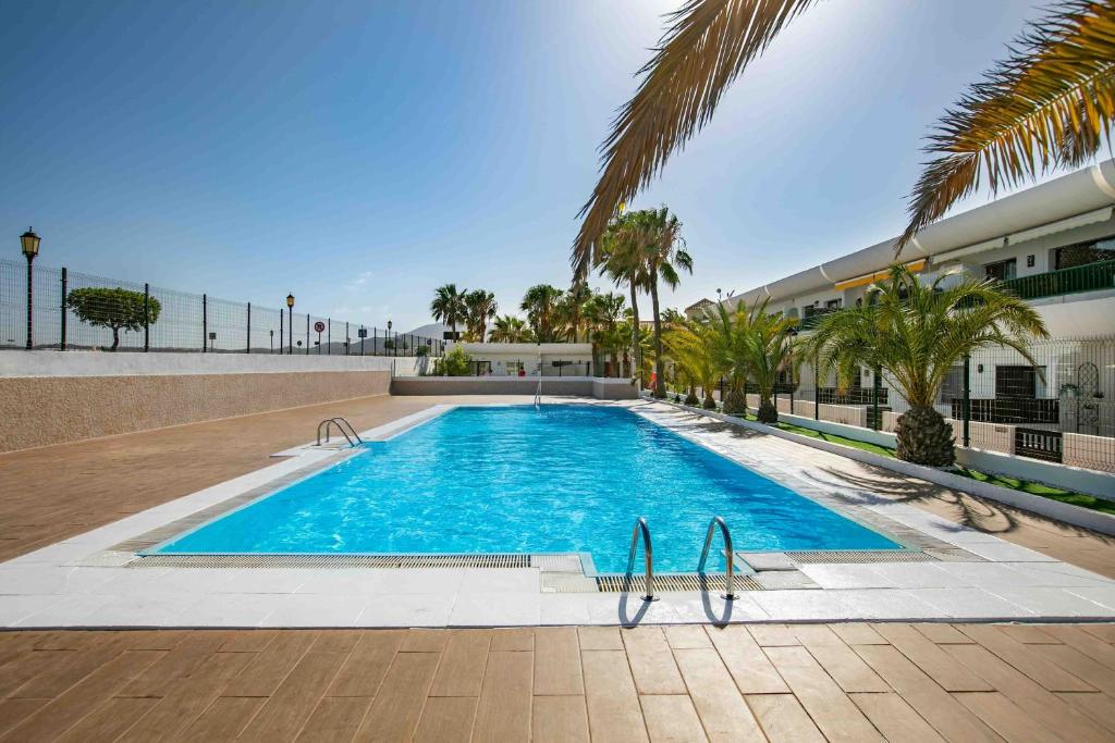 una piscina con palmeras y un edificio en Apartamentos Vistas Dunasol, en Corralejo