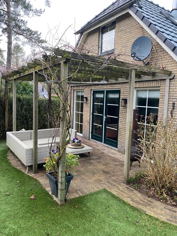 a house with a pergola and a bench in a yard at Hunting Lodge 104 in Lunteren