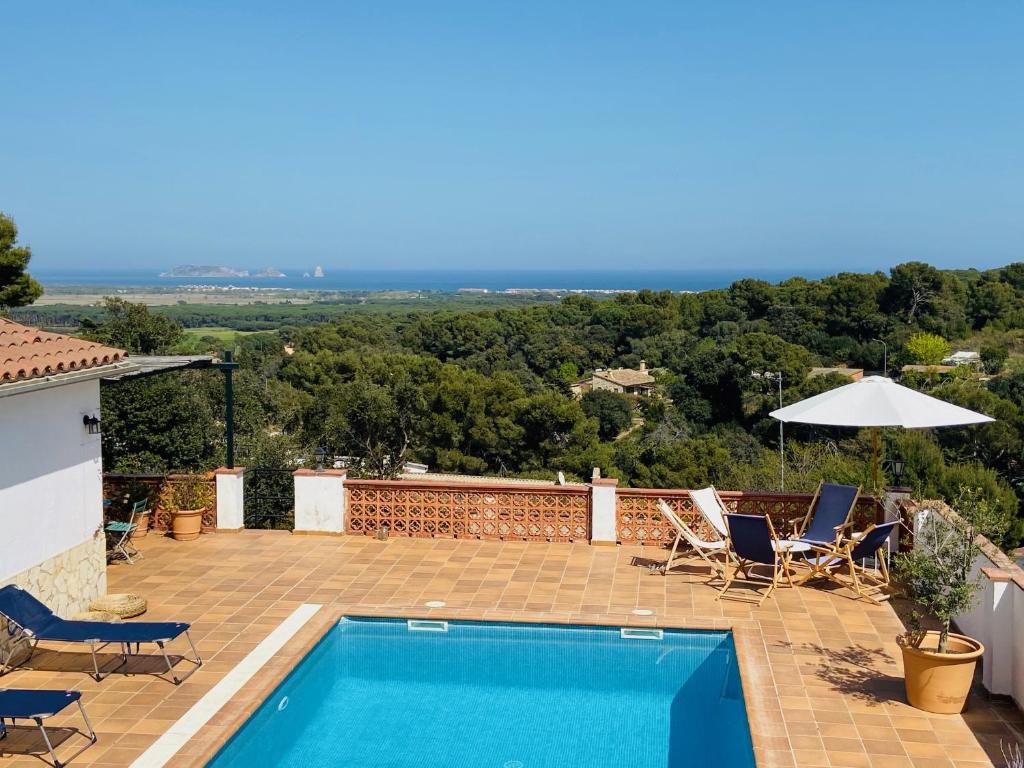een zwembad op een patio met stoelen en een parasol bij Jolie Villa vue mer - 100km au Nord de Barcelone - in Pals