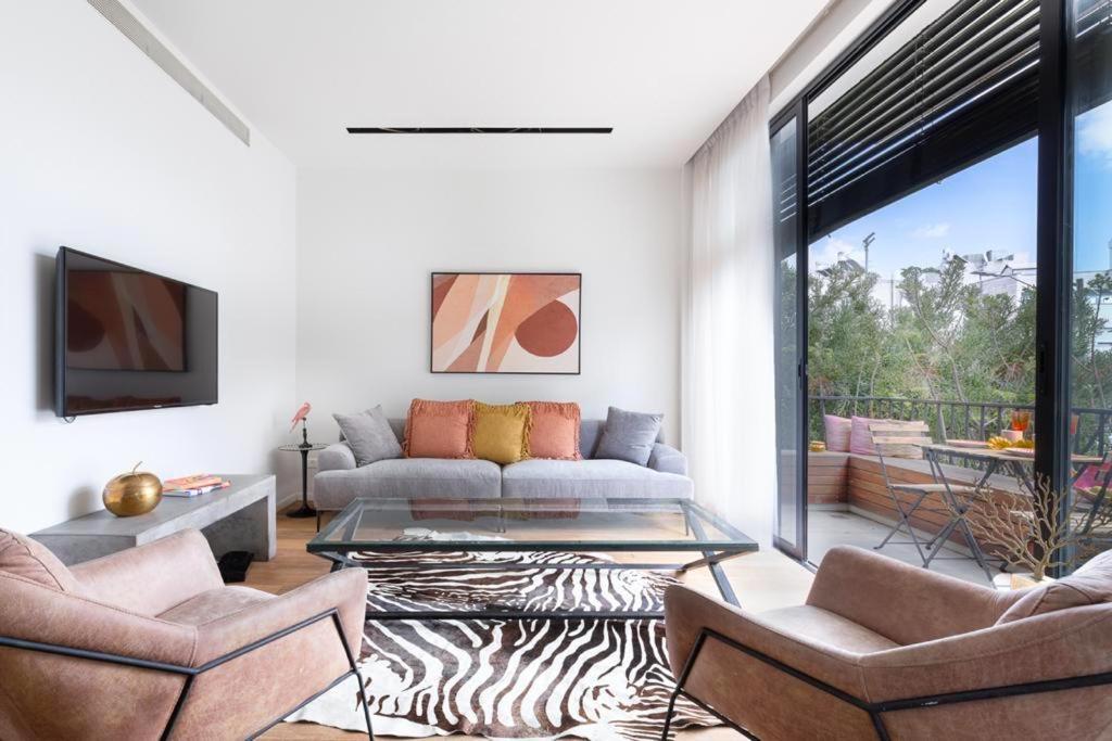 ein Wohnzimmer mit einem Sofa und einem Glastisch in der Unterkunft Frishman Dream by Five Stay in Tel Aviv