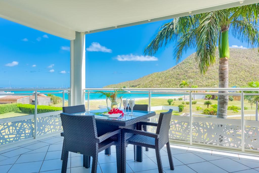 a table and chairs on a balcony with a view of the ocean at Le Domaine Anse Marcel Beach Resort in Anse Marcel 