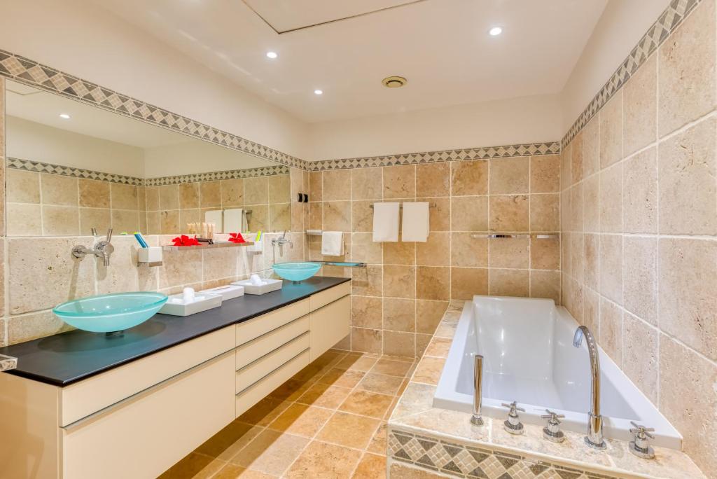 a bathroom with two sinks and a tub at Le Domaine Anse Marcel Beach Resort in Anse Marcel 