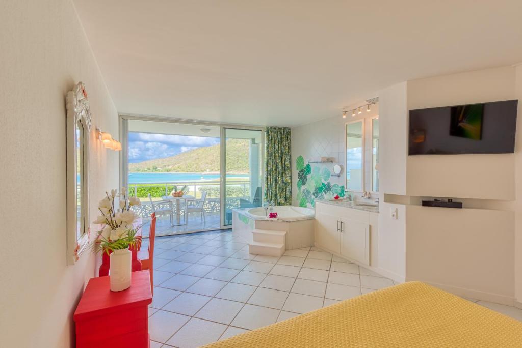 a bathroom with a tub and a sink and a toilet at Le Domaine Anse Marcel Beach Resort in Anse Marcel 