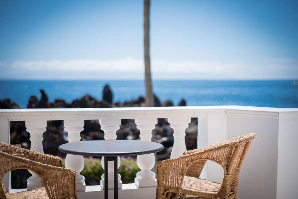 een tafel en 2 stoelen op een balkon met uitzicht op de oceaan bij Modern, cozy and peaceful oceanfront oasis in Puerto de Santiago