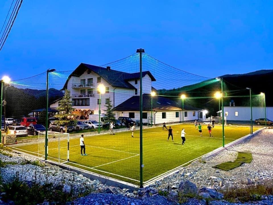 a group of people playing tennis on a tennis court at night at Pensiunea Mario & Ema in Cîrlibaba