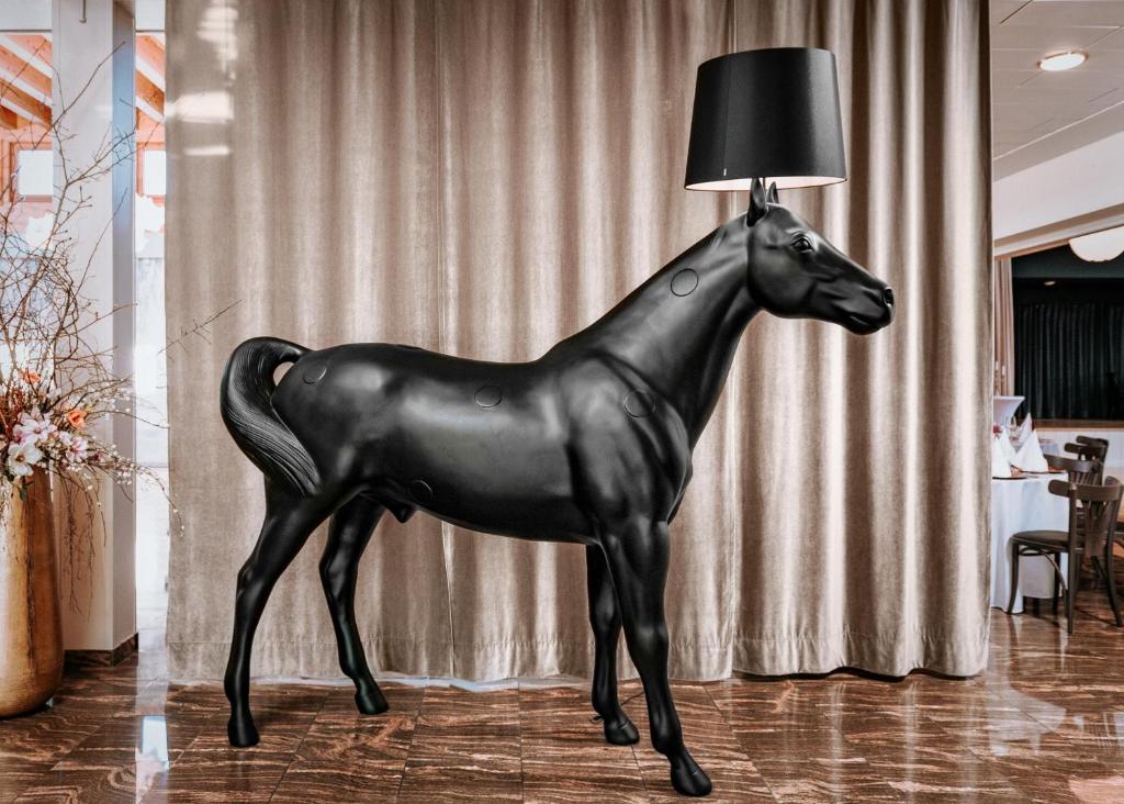 een zwart standbeeld van een paard met een lamp op de vloer bij Hydepark in Haidkapelle