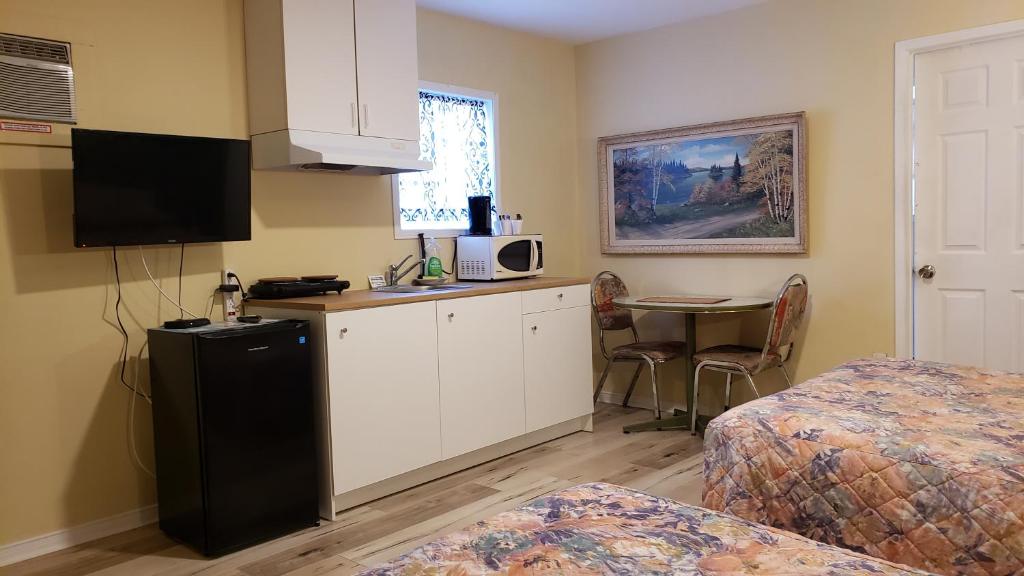 a room with a kitchen with a table and a microwave at Oakwood Motel in Gravenhurst