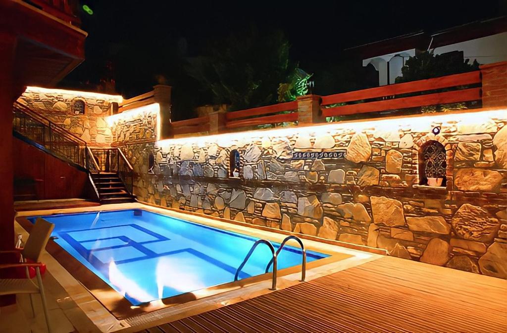 a large swimming pool with a stone wall at Ankakyaka Apart Hotel in Muğla