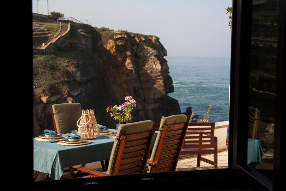 a table with a view of the ocean from a window at Um Lugar ao Sol Beach House Azenhas do Mar in Sintra