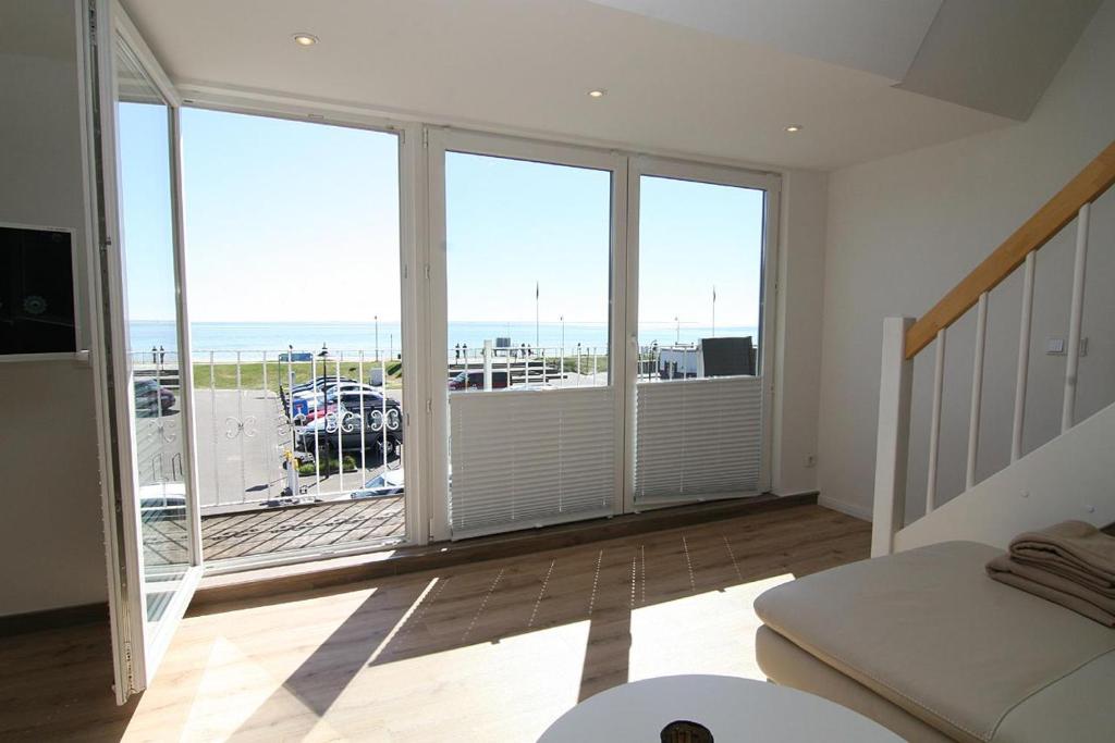 a bedroom with a balcony with a view of the ocean at Am Wasser 4 OG in Hörnum