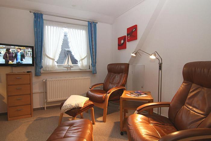 a living room with two leather chairs and a television at Haus Gräpel App 2 in Hörnum