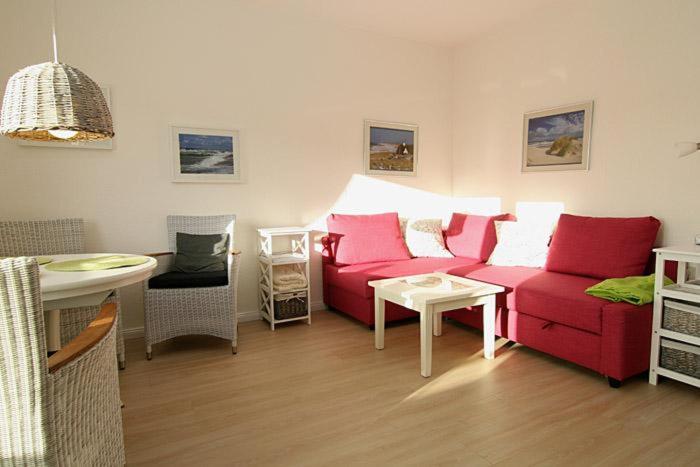 ヘルヌムにあるHaus Möwe Wohnung Gonnermannのリビングルーム(赤いソファ、テーブル付)
