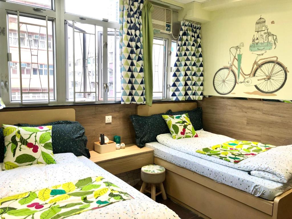 ein Zimmer mit 2 Betten und einem Fahrrad an der Wand in der Unterkunft Paris Guesthouse-Tsim Sha Tsui Mansion in Hongkong