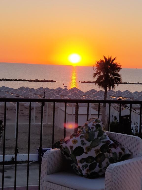 un tramonto sulla spiaggia con una sedia sul balcone di il Sorriso di Angelina a Pescara