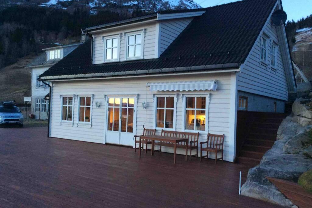 a white house with chairs and a table in front of it at Flohytta in Stryn