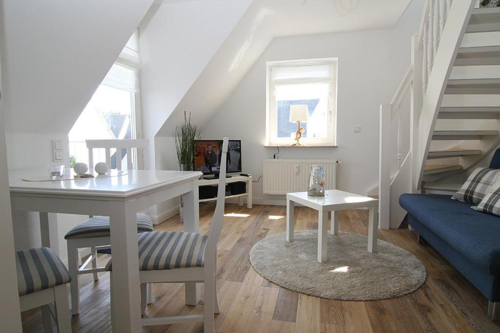 a white living room with a table and a blue couch at Seaside 4 in Hörnum