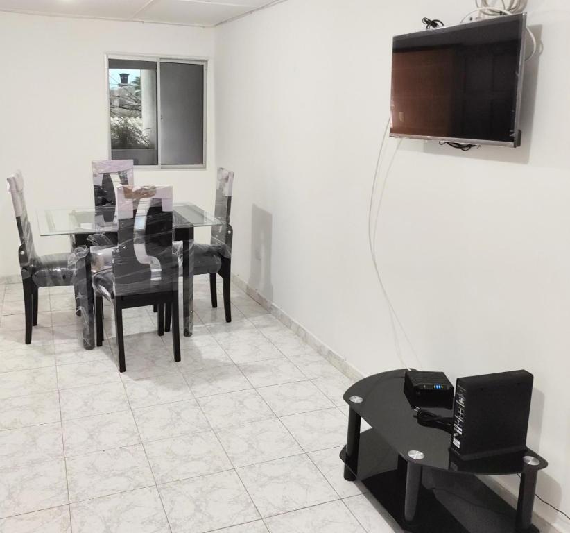 ein Esszimmer mit einem Tisch, Stühlen und einem TV in der Unterkunft Apartamentos Riohacha in Ríohacha