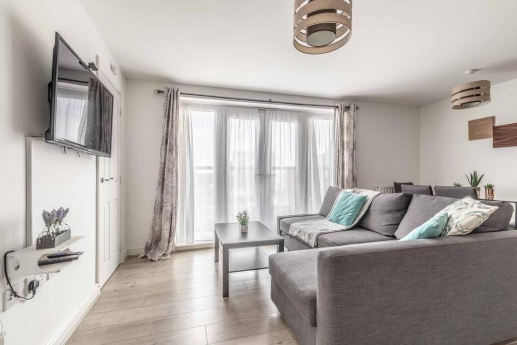 a living room with a couch and a tv at 2 BED & 2 BATH COSY APARTMENT SLOUGH- FREE PARKING in Slough