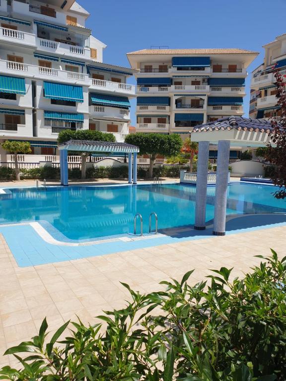 a swimming pool in front of a large building at LUX Apartamento in La Mata