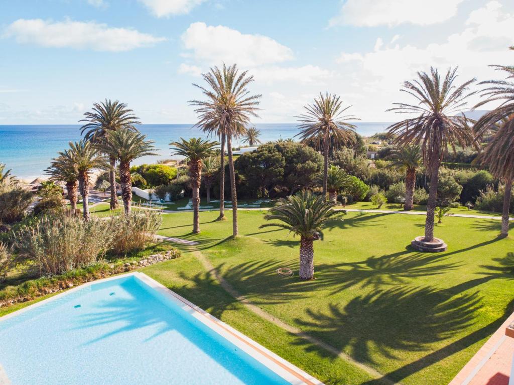 uma imagem de uma piscina com palmeiras e o oceano em Hotel Porto Santo & Spa em Porto Santo