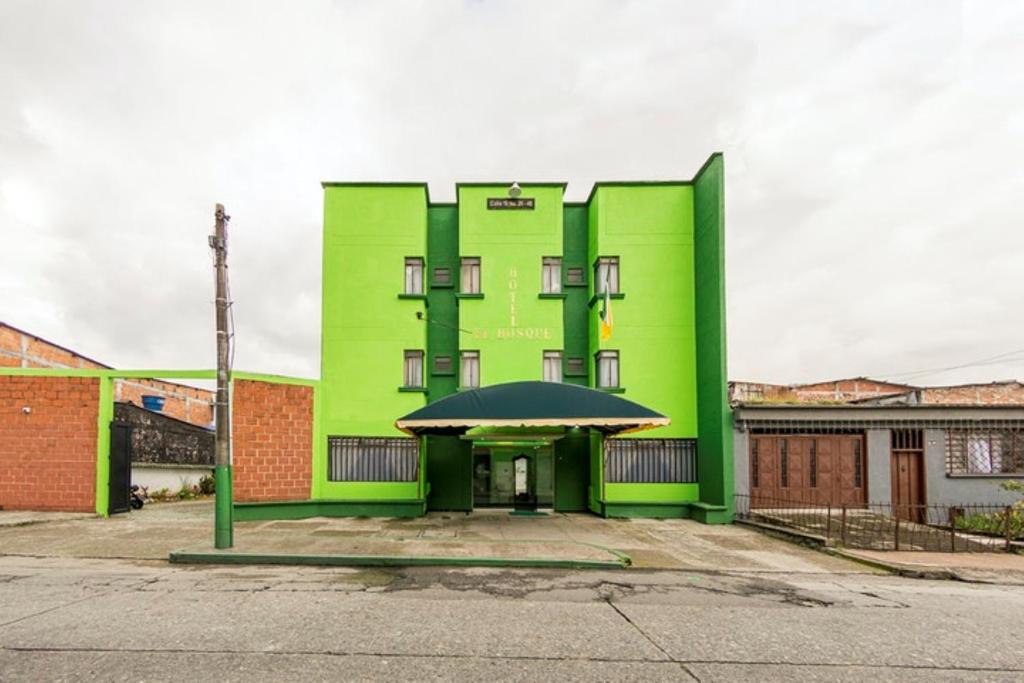 a green building with a black umbrella in front of it at Hotel El Bosque in Armenia