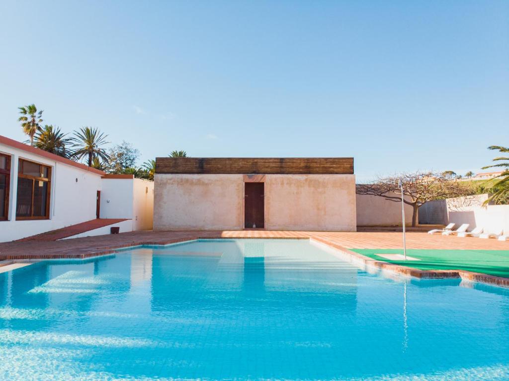 a swimming pool in front of a house at Hotel Porto Santo & Spa in Porto Santo