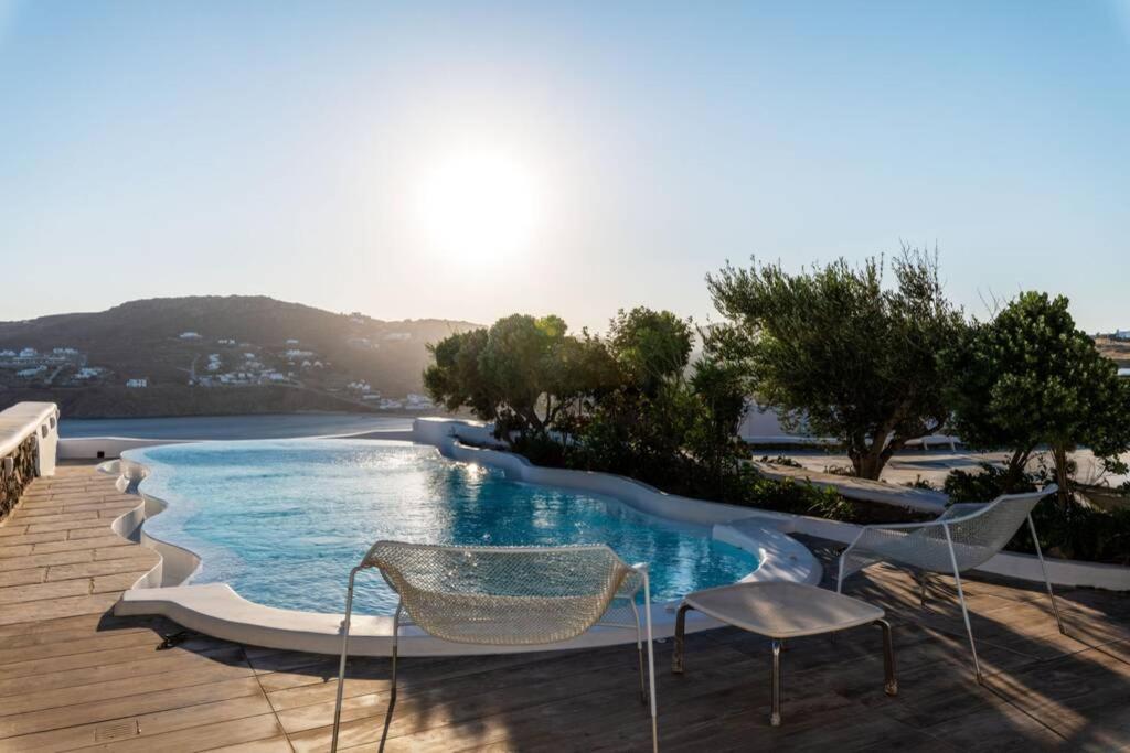 a swimming pool with two chairs and a table at Cycladic Luxury and Comfort in Kalo Livadi in Kalo Livadi