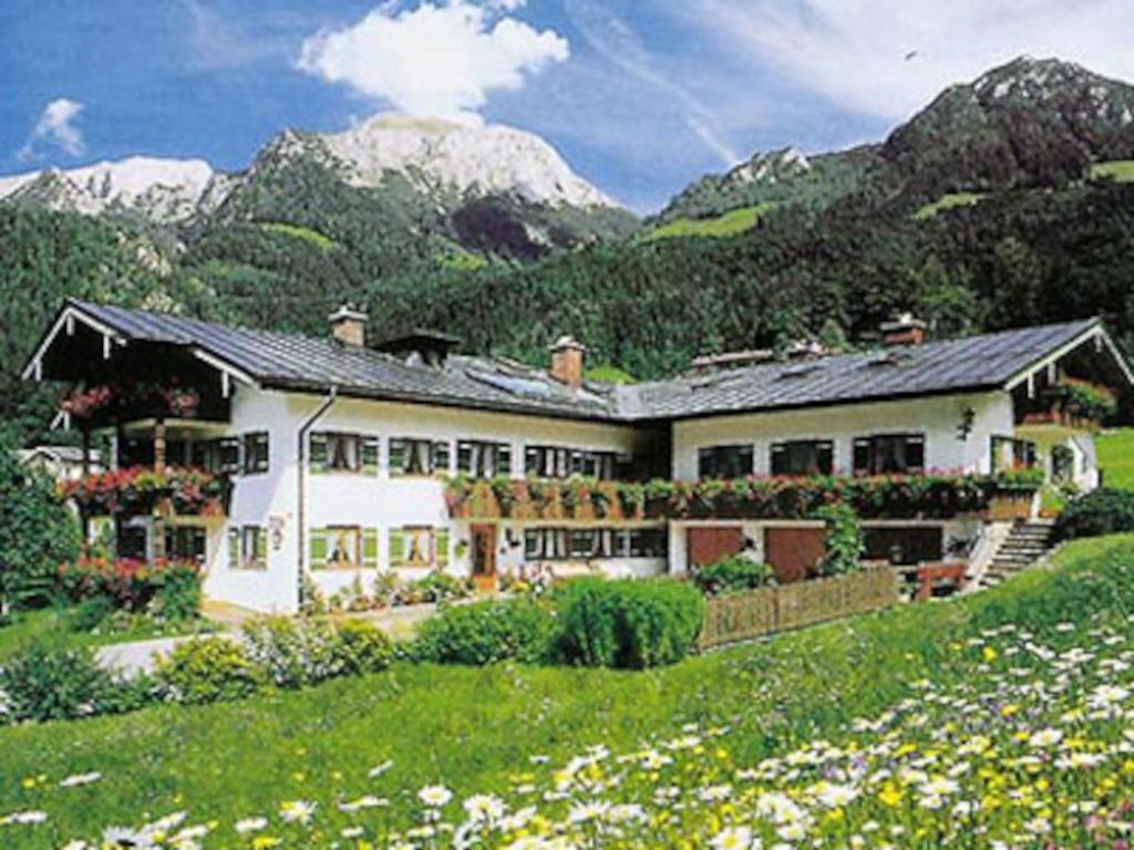 a large white house with mountains in the background at Pension Neuhausen in Schönau am Königssee