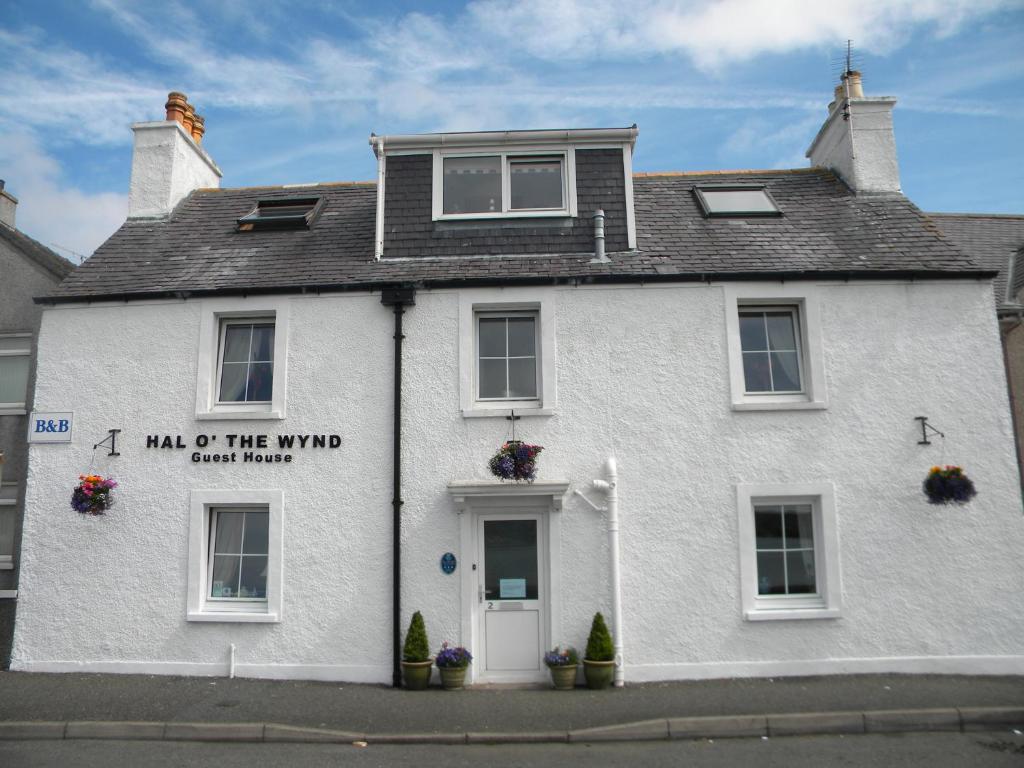 a white house with a sign on the front of it at Hal O' The Wynd Guest House in Stornoway