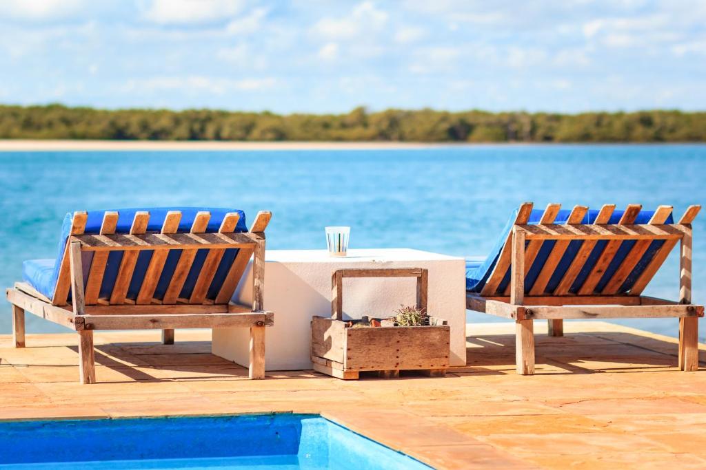 2 sillas y una mesa junto a la piscina en Pousada Oásis Galinhos - Experiências Únicas para Pessoas Únicas, en Galinhos