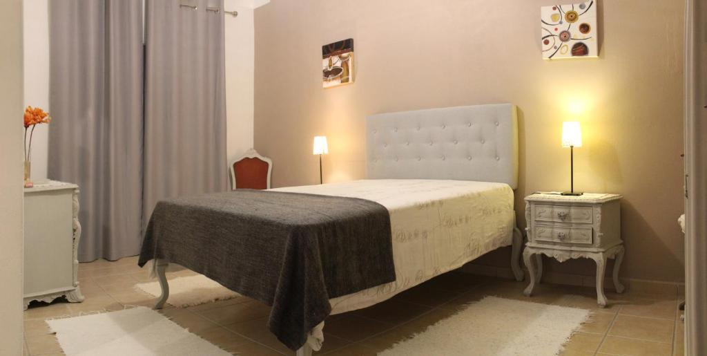 a bedroom with a bed and a nightstand with two lamps at Casa Luz in Vila Nova de Milfontes