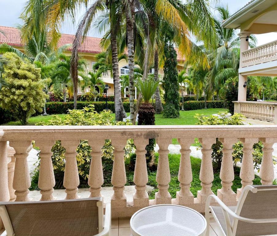 a balcony with a table and chairs and palm trees at La Ensenada Beach Resort in Tela