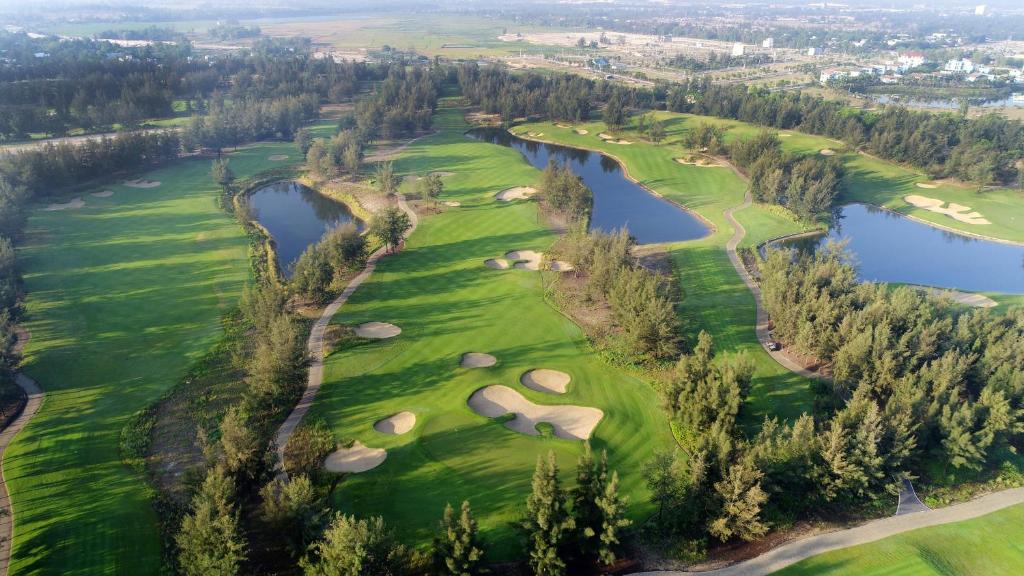 an aerial view of a golf course with a lake at Montgomerie Links Hotel & Villas in Hoi An