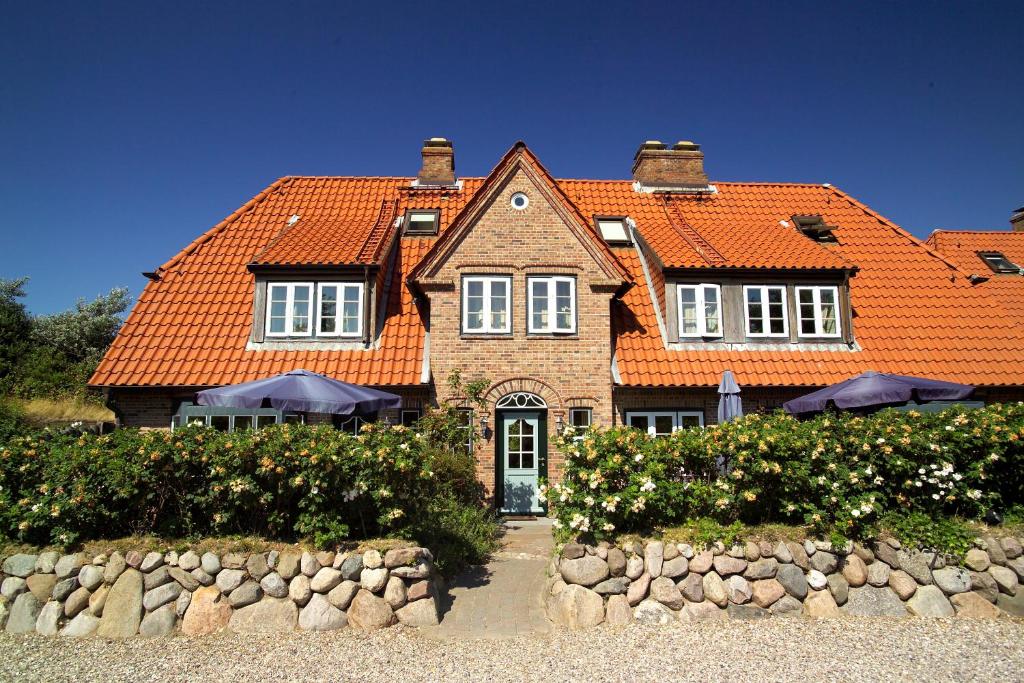 ein großes Haus mit orangefarbenem Dach in der Unterkunft Ferienhäuser im Sylter Gartenweg in Tinnum