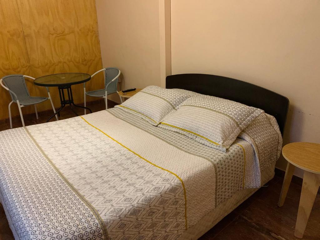 a bedroom with a bed with a table and chairs at Hostal Iria in Antofagasta