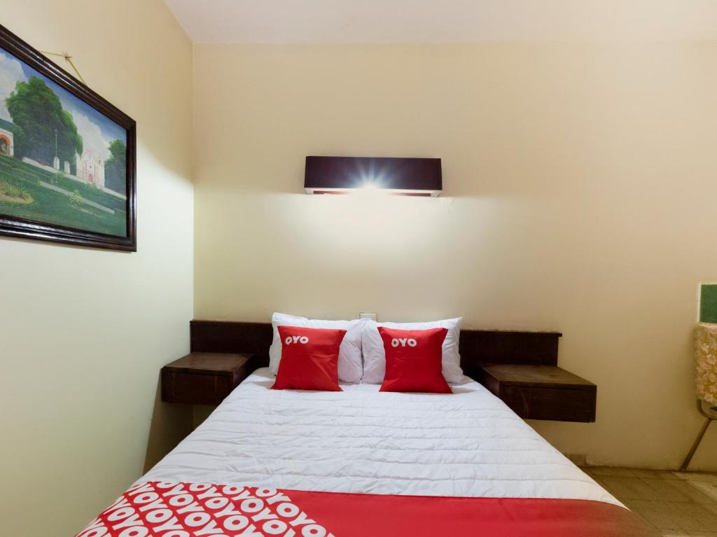 a bedroom with a bed with red pillows at OYO Hotel Emperador, Oaxaca in Oaxaca City