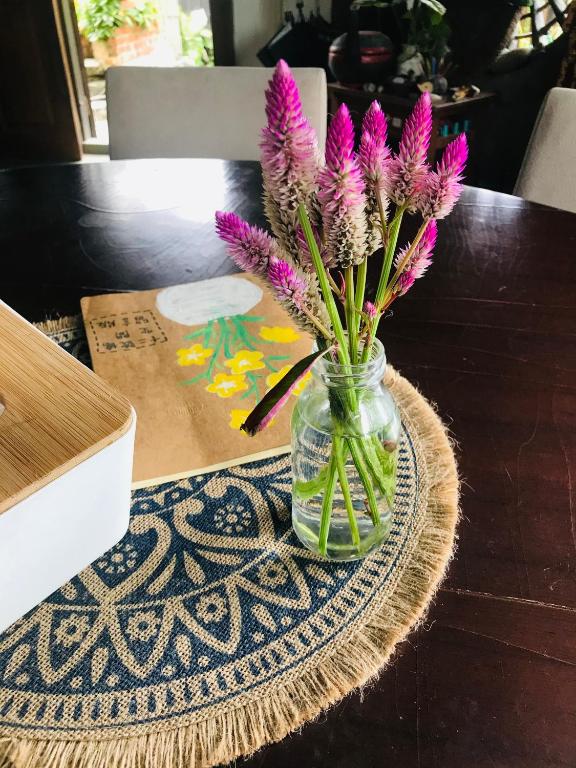 a mason jar with purple flowers in it on a table at Bridge12th B&amp;B in Yanliau