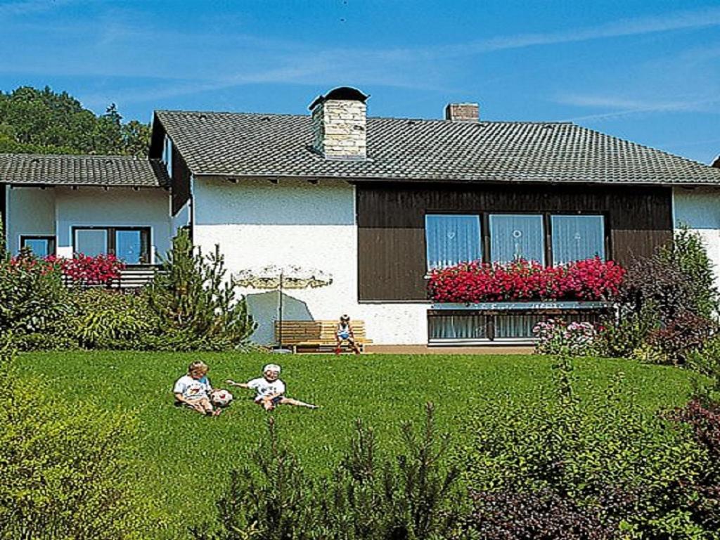 zwei Kinder sitzen im Gras vor einem Haus in der Unterkunft Ferienwohnung Keckl in Beilngries