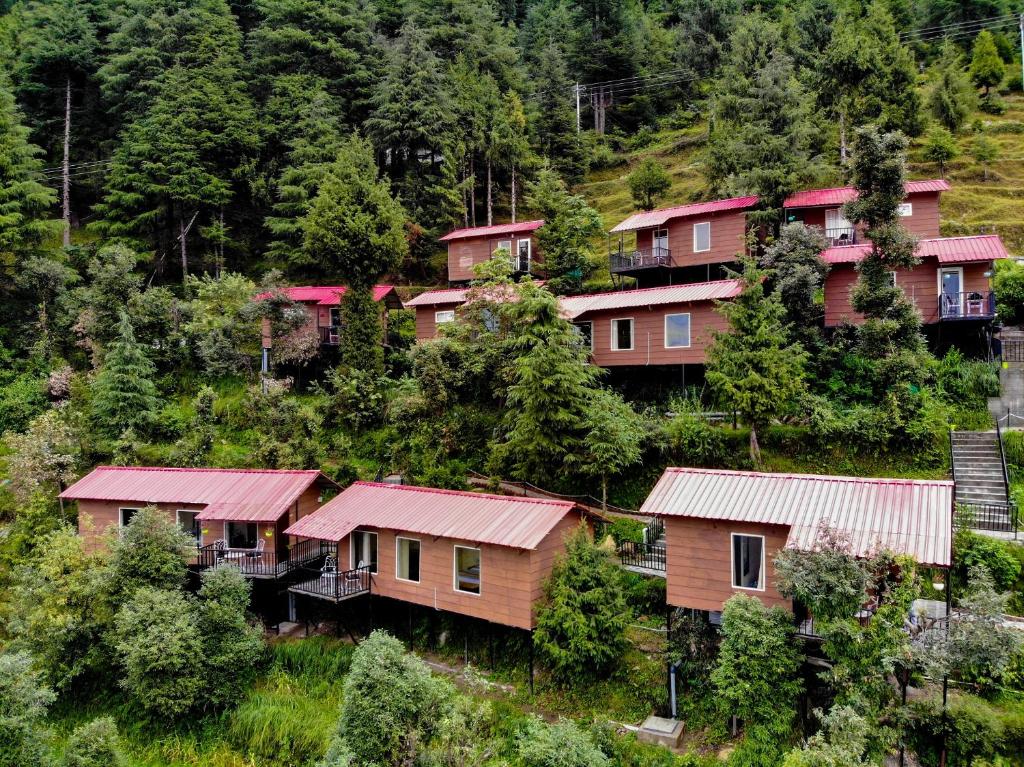a group of cabins on a hill with trees at Aaroham By Aamod Luxury Cottage Resort in Dalhousie