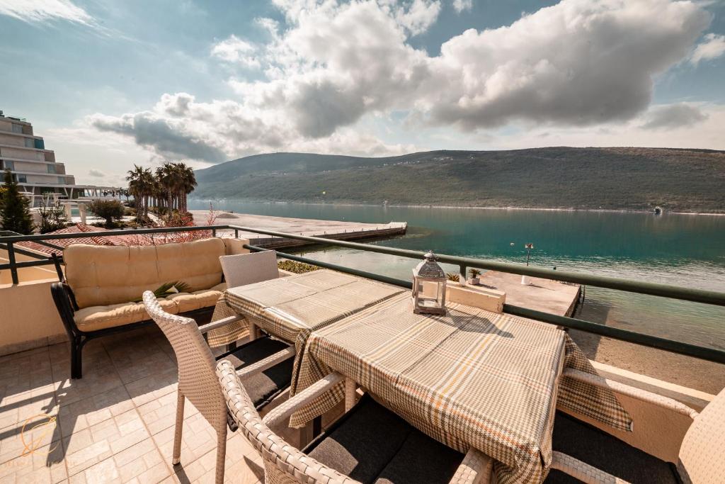 a table and chairs on a balcony with a view of a lake at Apartments Batricevic in Herceg-Novi