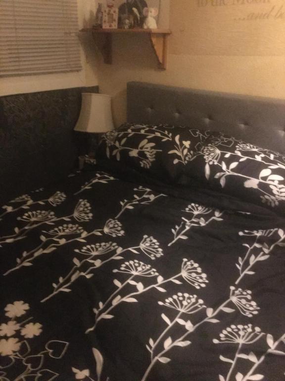 a bed with a black and white blanket on it at Little Trains of Dartmouth in Dartmouth