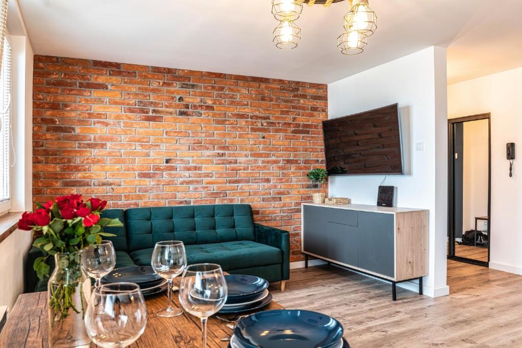 a living room with a green couch and a brick wall at Apartament Loft in Giżycko