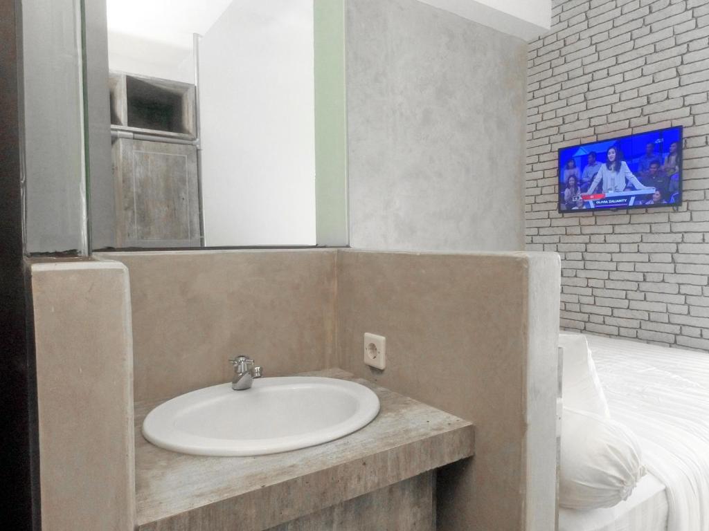 baño con lavabo y TV en la pared en DPARAGON GAJAH MADA en Yakarta