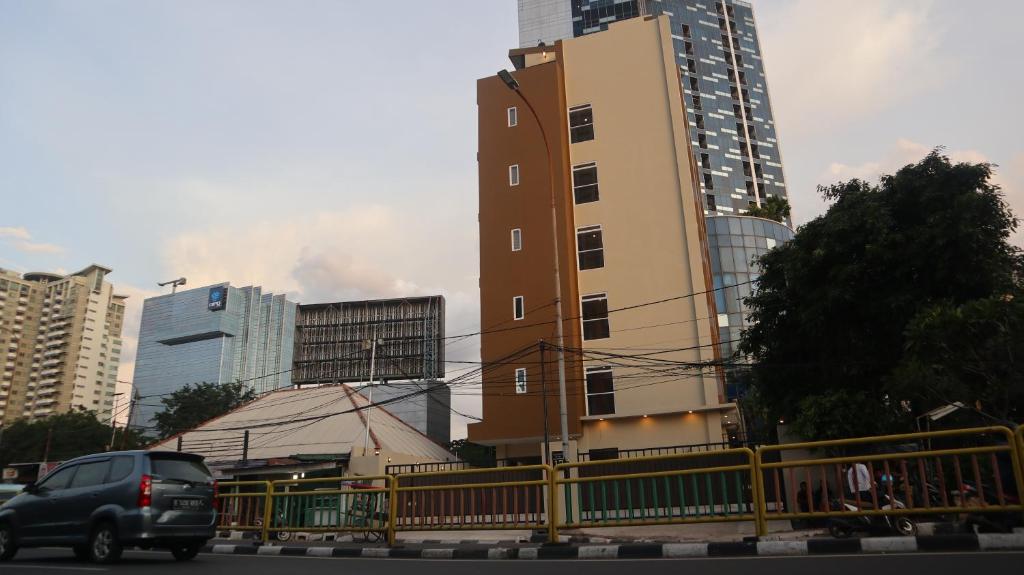 Una furgoneta conduciendo por una calle al lado de un edificio alto en DJURAGAN KAMAR SLIPI, en Yakarta