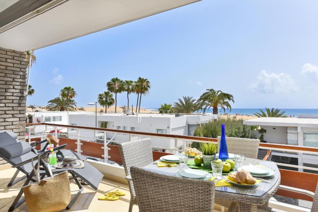 una mesa en un balcón con vistas a la playa en Apartment Oasis CM18 by VillaGranCanaria en Maspalomas